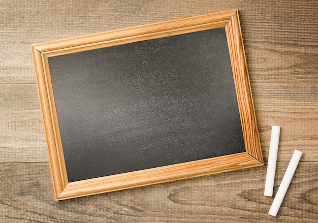 empty blackboard and two chalks on a wooden saute