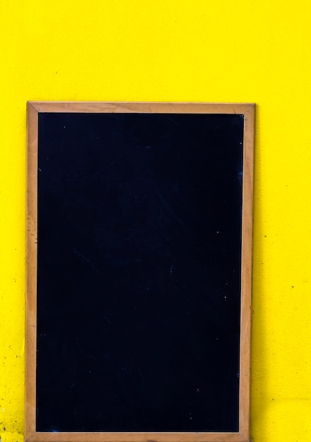 empty blackboard with yellow wall background