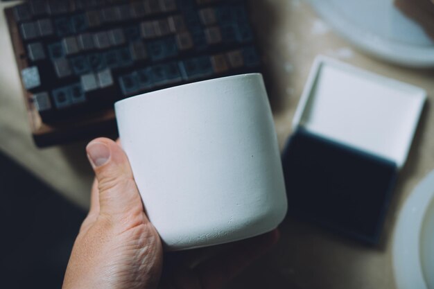 Empty blanc white concrete candle jar in artist's hand creative painting and design ready ceramic