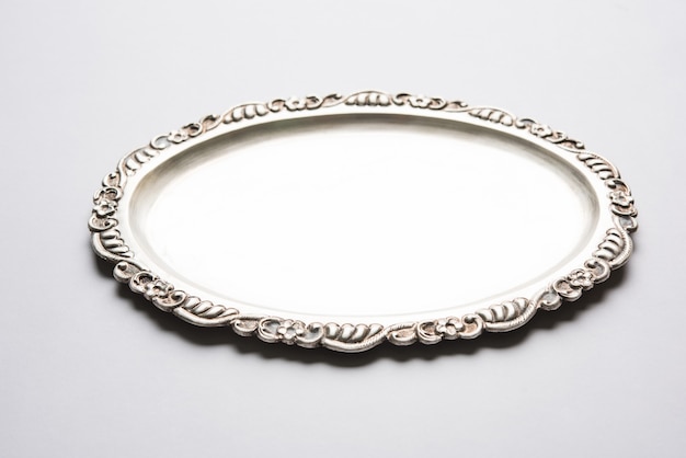 empty or blank silverware or oval shape silver plate with decorative border, isolated over white surface, selective focus