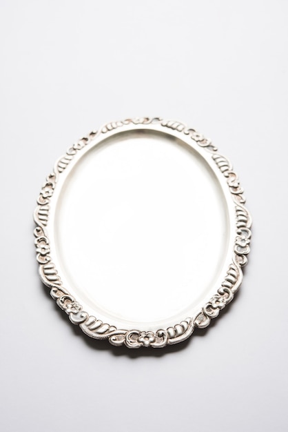 empty or blank silverware or oval shape silver plate with decorative border, isolated over white surface, selective focus