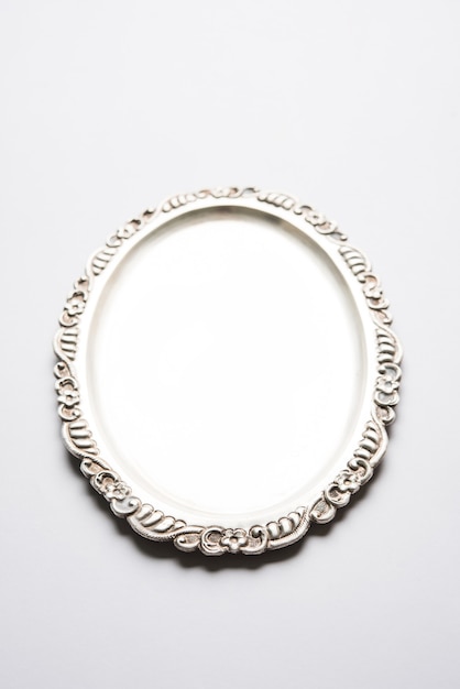 Empty or blank Silverware or Oval Shape Silver Plate with decorative border, isolated over white surface, selective focus