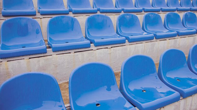 Empty bleacher in sports stadium in rainy weather Colored wet seats in street stadium It's raining Close up