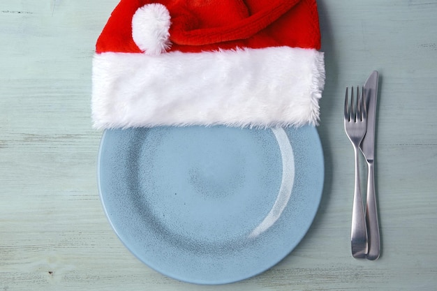 파란색 나무 테이블 크리스마스 서빙에 크리스마스 모자와 칼 붙이와 빈 파란색 접시 접시