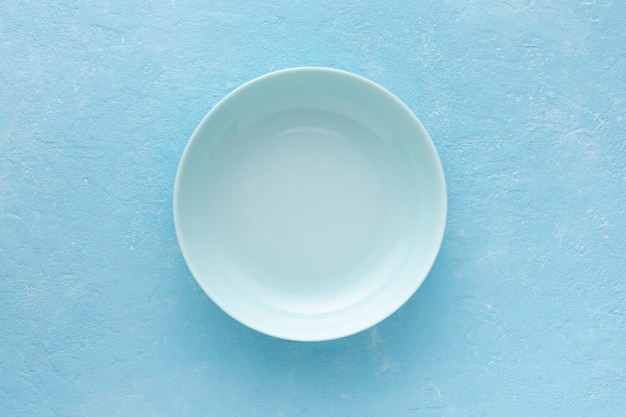 Empty blue plate on a light blue