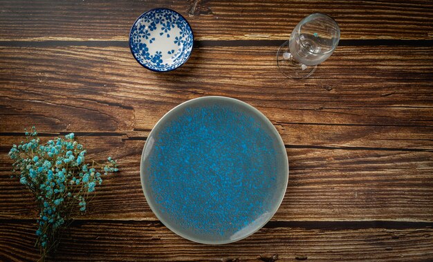Пустая синяя тарелка и ложка на деревянном фоне макет сверху