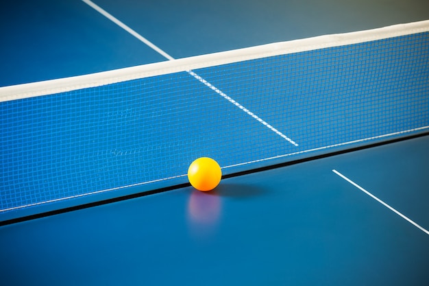 Empty blue table with a net and a yellow ball