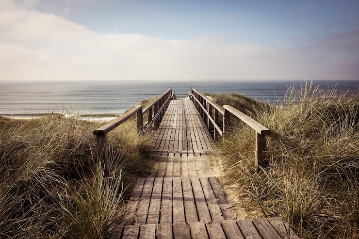 Photo empty boardwalk leading to calm sea against cloudy sky