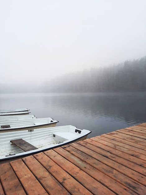 桟橋で空のボートと湖の上の霧