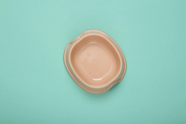 Empty bowl for cat food on blue background Top view