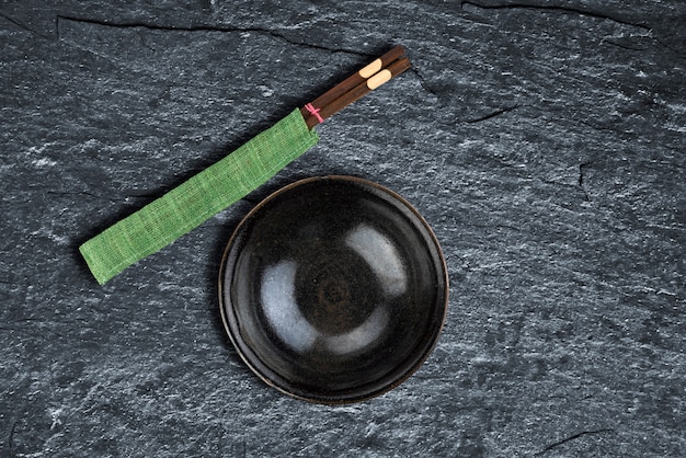 Empty bowl and chopsticks over background texture