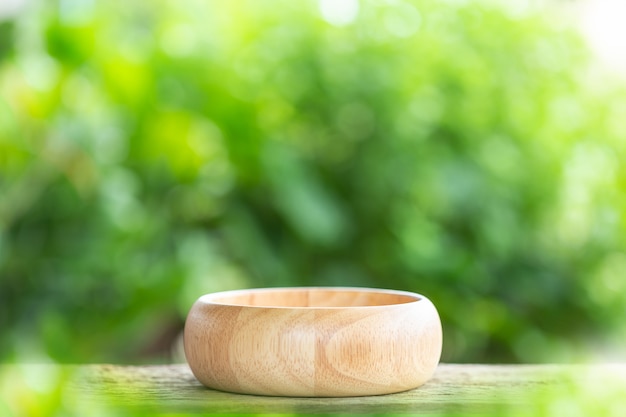 Empty bowl on wooden table with green blur light background