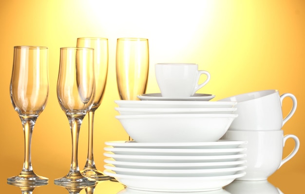 Photo empty bowls plates cups and glasses on yellow background