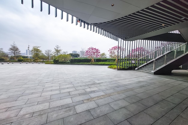 空のれんが造りの床と緑の木の背景を持つ都市公園のモダンな建物