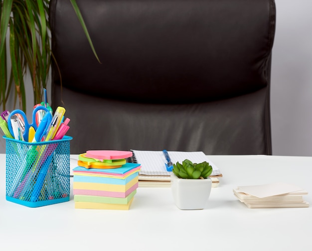 Empty brown armchair and white desk with stationery