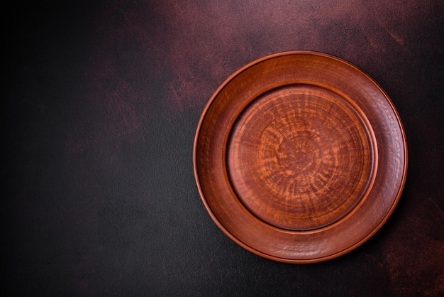 An empty brown ceramic plate on a dark concrete brown background