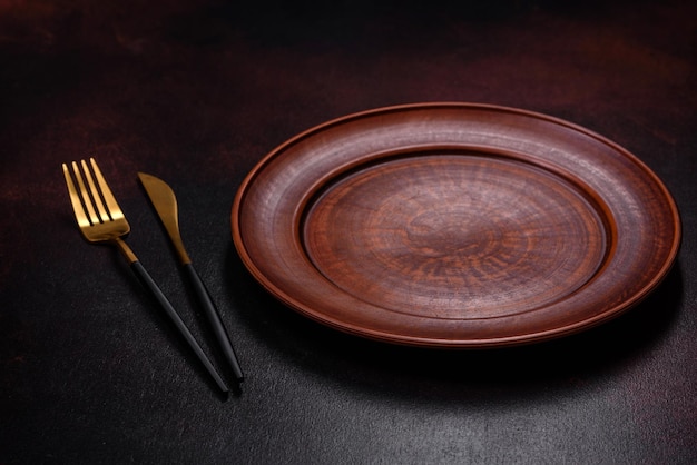 An empty brown ceramic plate on a dark concrete brown background