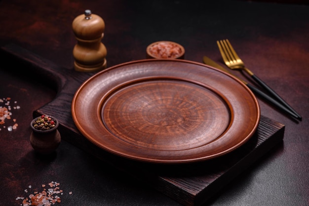 An empty brown ceramic plate on a dark concrete brown background