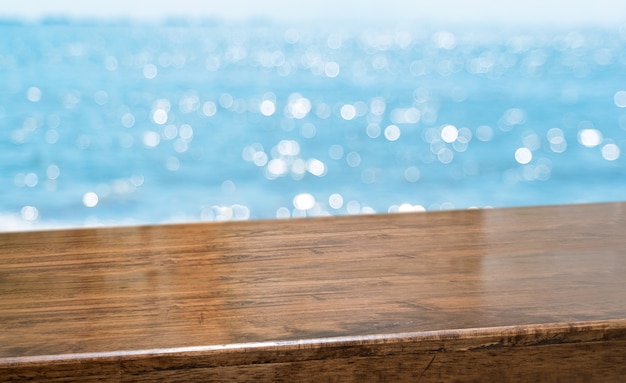 Photo empty brown glossy wood table top with blur sky and sea boekh background
