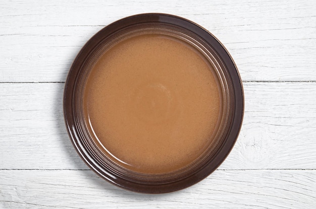 Empty brown plate on white wooden background, top view