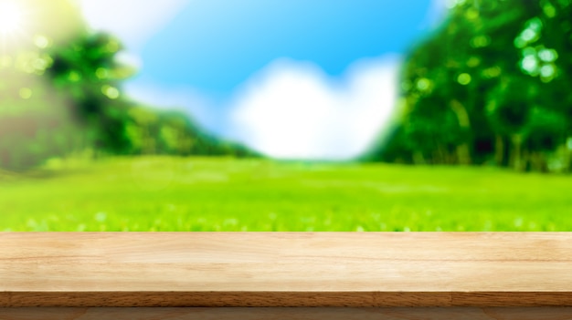 Empty brown wooden table top with blurred green fields at park