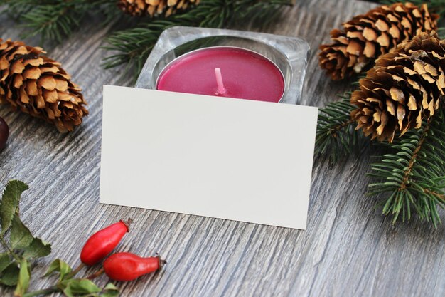 Foto mockup di biglietto da visita vuoto con decorazioni natalizie e candela sullo sfondo del tavolo in legno mock up per l'identità del marchio modello vuoto per il tuo design
