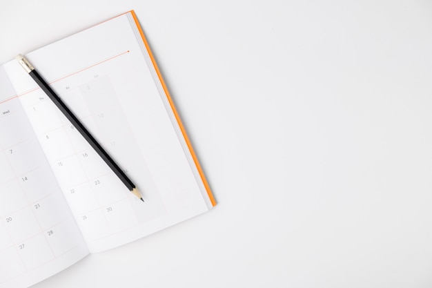 Empty Calendar book and pencil on white isolated background, top view, copy space 