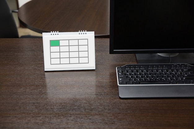 Empty calendar on working table with computer display in office