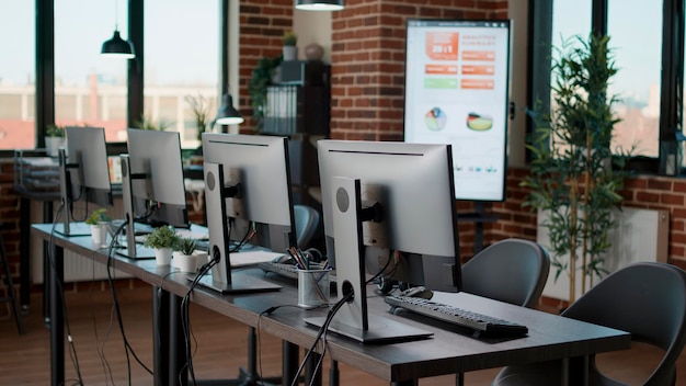 Empty call center office with computers and monitors on desk, using technology to give support to clients at customer service helpline. Nobody in business space with telemarketing workstation.