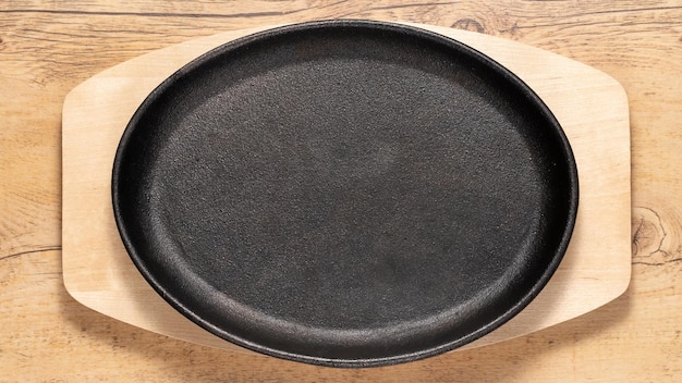 Empty cast iron black plate on a light wooden background