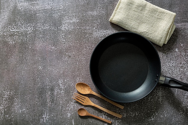 Empty cast iron frying pan on dark grey culinary background view from above