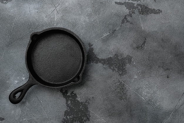 Empty cast iron skillet set with copy space for text or food with copy space for text or food, top view flat lay, on gray stone table background