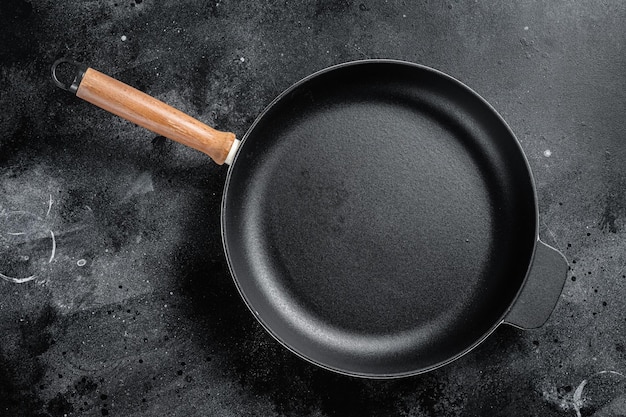 Photo empty castiron skillet for cooking on rustic towel black background top view copy space