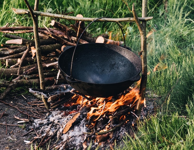 An empty cauldron warms up on a fire in the forest before cooking