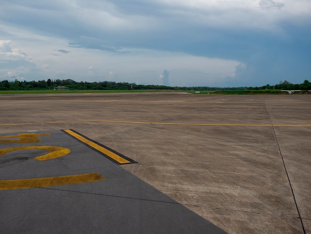 写真 雨雲の空と田舎の空港の空のセメント滑走路道路