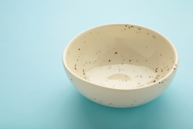 Empty ceramic bowl on blue background