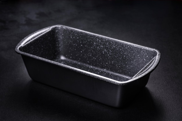 An empty ceramic grey baking dish on a dark concrete background Preparation for baking tasty cupcake