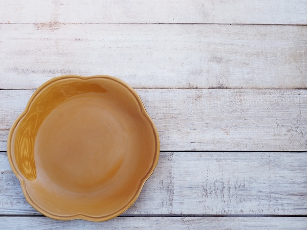 Photo empty ceramic plate flower shape on wooden background