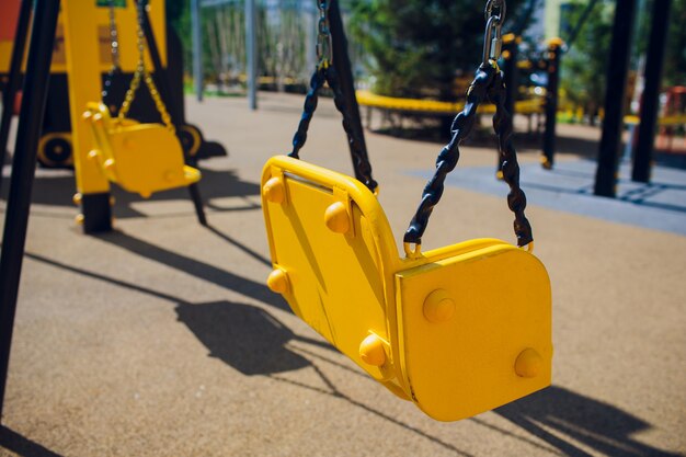 Empty chain swing swings in children playground.