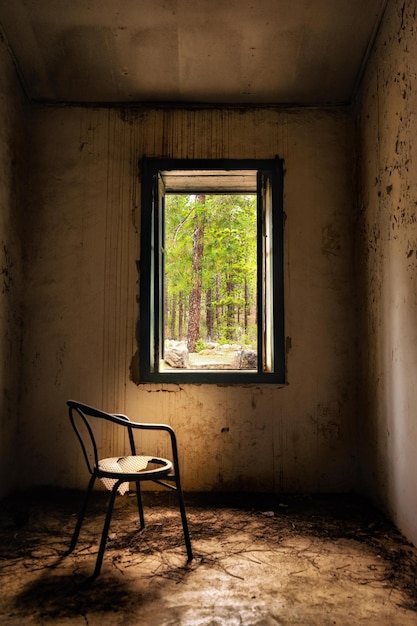Foto una sedia vuota accanto alla finestra di una stanza abbandonata.