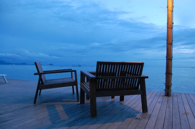 Empty chairs on beach against sky