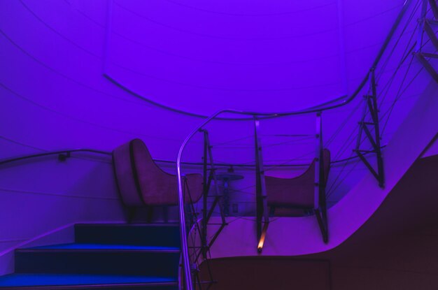 Empty chairs on staircase in illuminated room