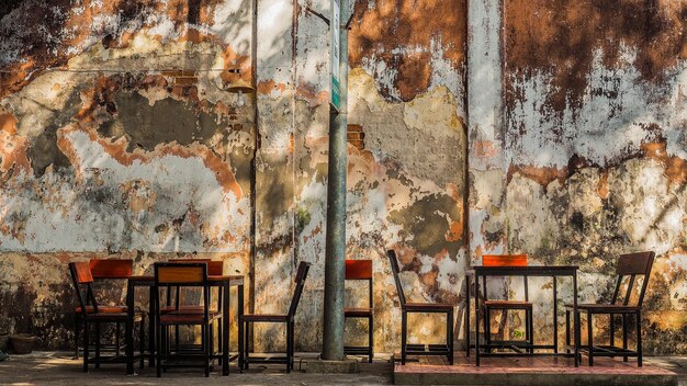 Photo empty chairs and table against wall in old building