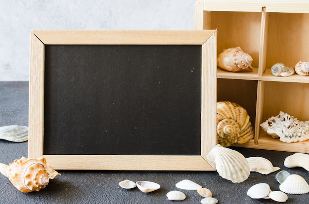 Photo empty chalkboard or photo frame with seashells.