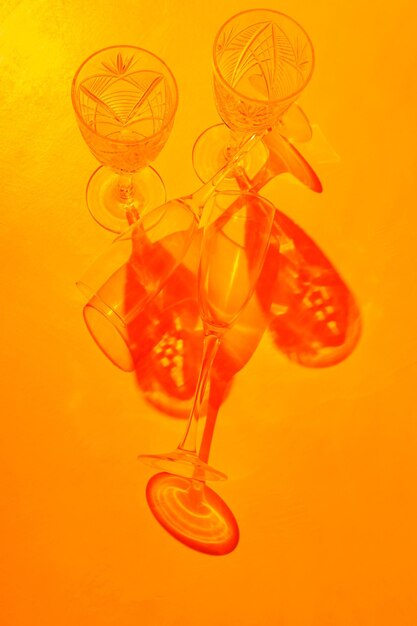 Empty champagne glasses with shadows on an orange background. Glassware in the sunset light. Minimalism. Copy space