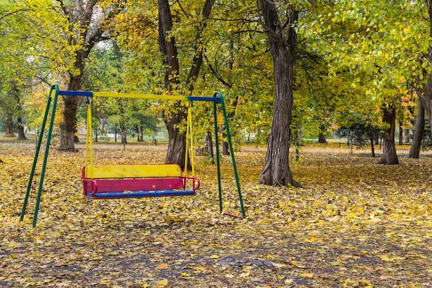 秋の都市公園で空の子供たちのブランコ