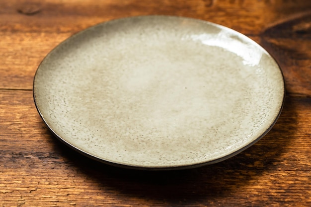 Empty clay plate on dark wooden background