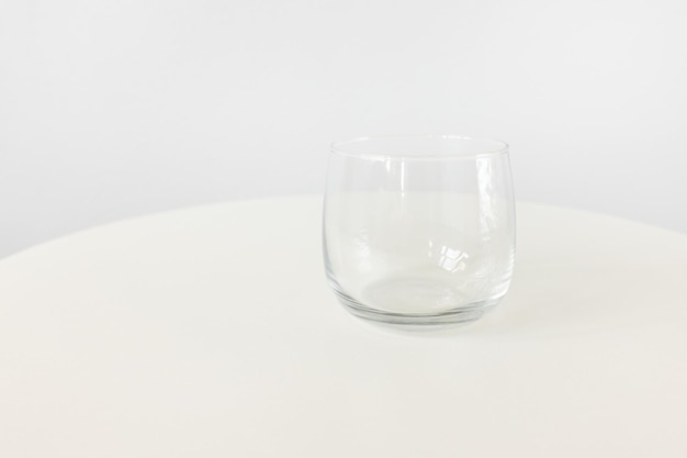 Empty clear small juice or water glass on white table background