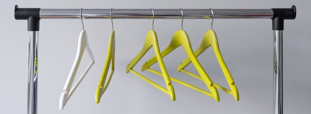 Empty clothes hangers on metal rail on grey