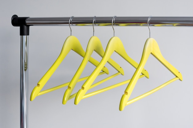 Empty clothes hangers on metal rail on grey